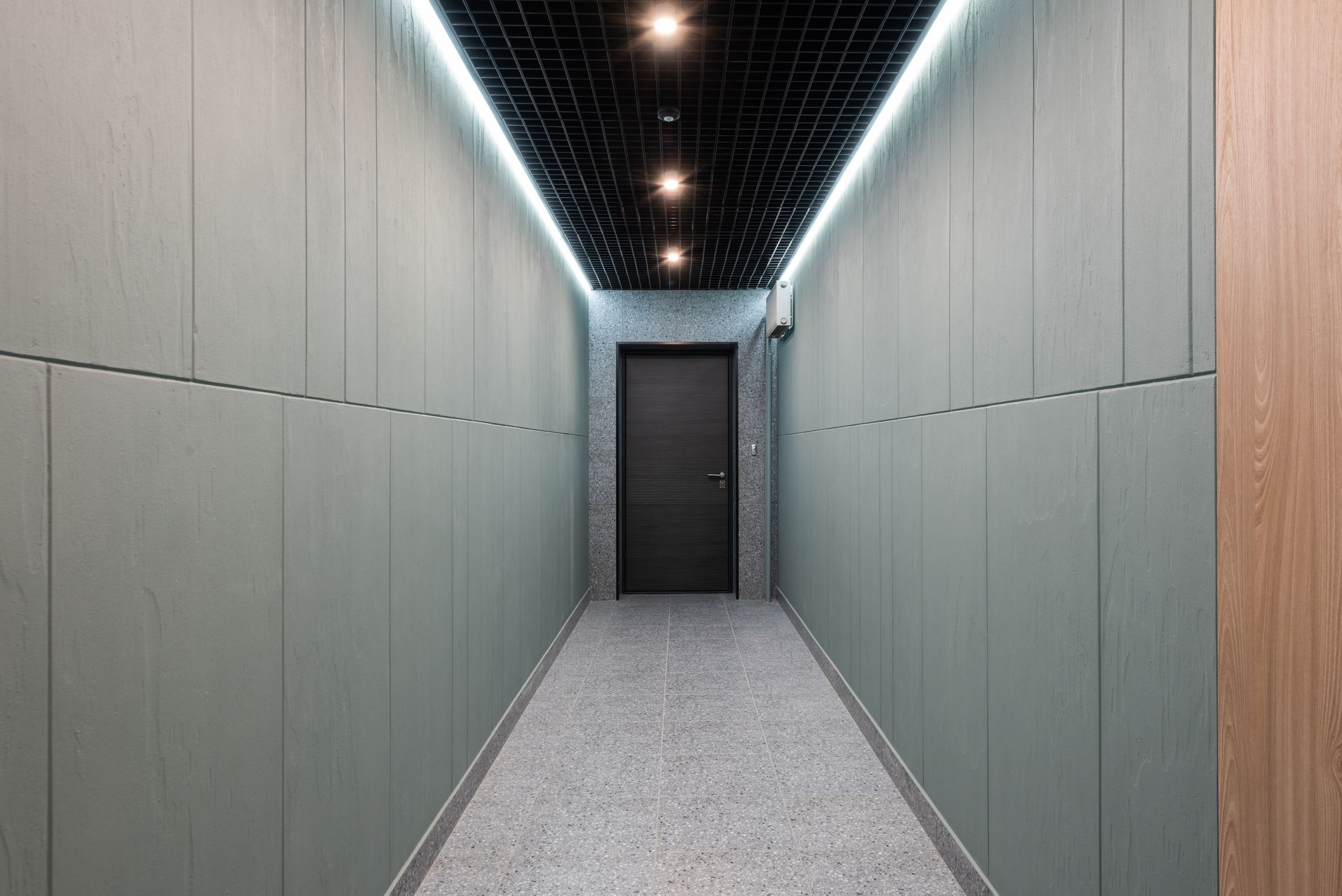 Couloir de bureaux avec plafond suspendu à trame et éclairage linéaire intégré
