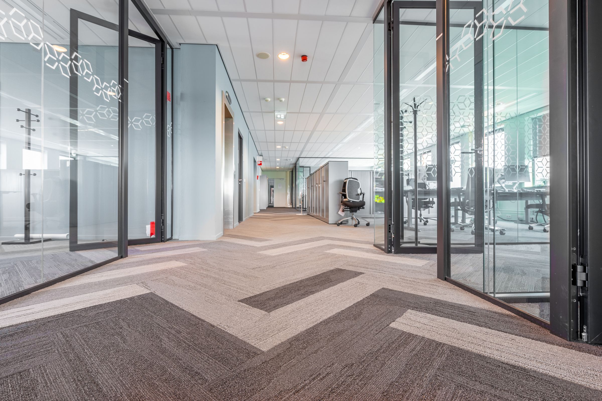 Couloir de bureaux sur dalles de moquette, cloisons vitrées et plafond suspendu